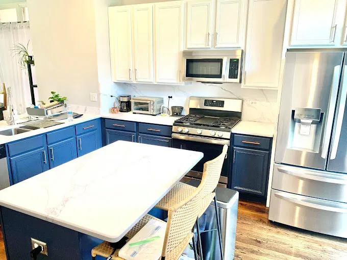 Kitchen with white upper cabinets and a navy blue painted island in a Chicago suburban home