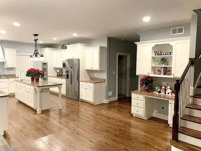 White kitchen cabinets and island beside a staircase and built-in desk