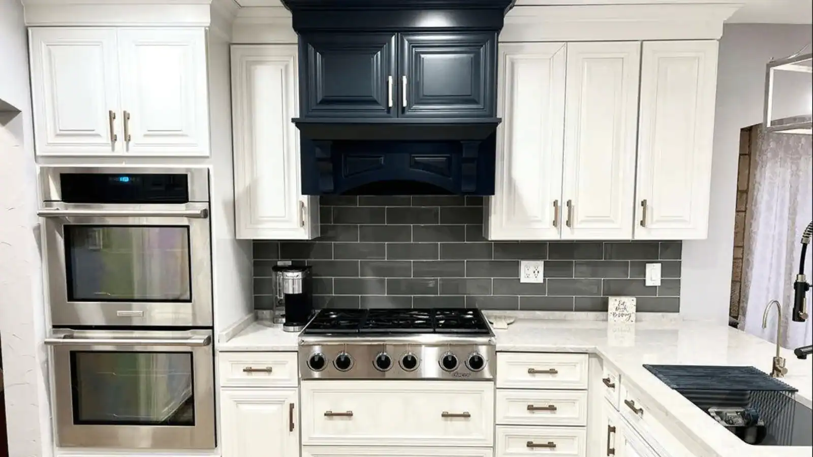 White painted kitchen cabinets with a navy blue range hood and gray tile backsplash