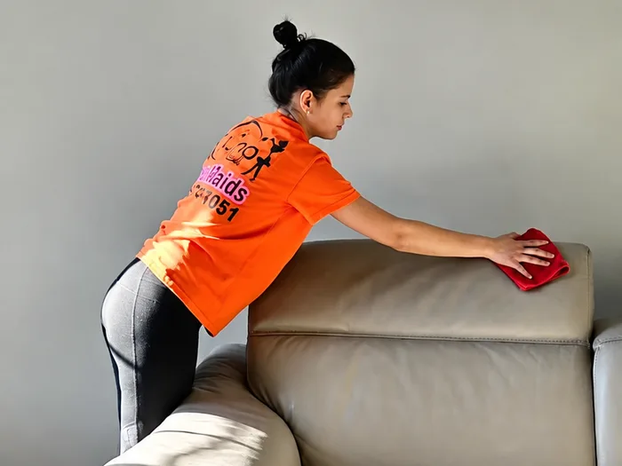 House cleaning service: a cleaner wiping down a leather sofa with a microfiber cloth