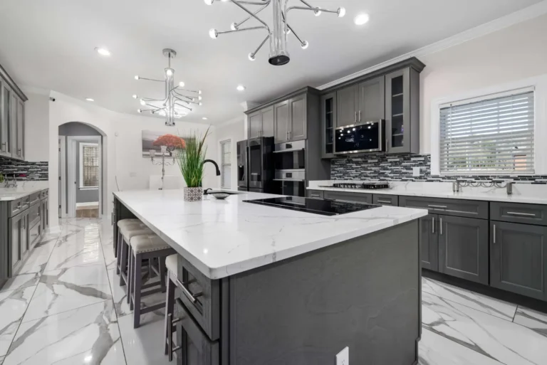 Dark gray kitchen cabinets and island with white countertops and a marble-look floor