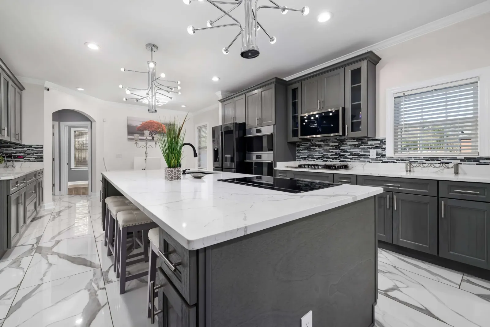Dark gray kitchen cabinets and island with white countertops and a marble-look floor