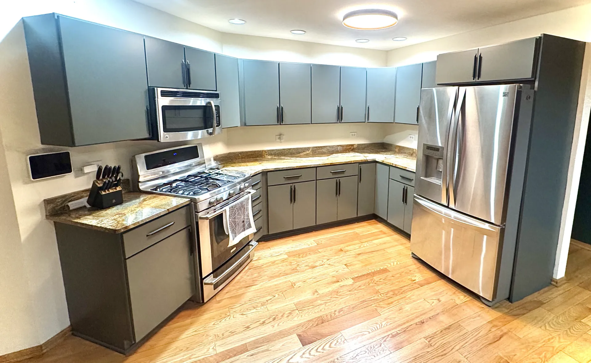 Kitchen with gray painted cabinets, stainless steel appliances and wood floors