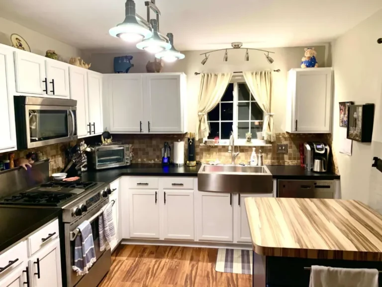 White refinished kitchen cabinets with dark countertops and a butcher-block island in a Chicago home