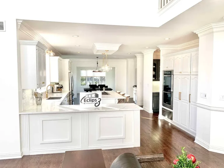 Wide view of white kitchen cabinets, paneled island ends and floor-to-ceiling pantry cabinets