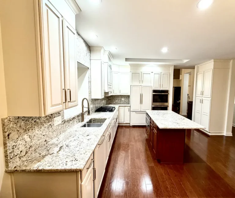 Finished white kitchen cabinets along a granite countertop with a wood-toned island